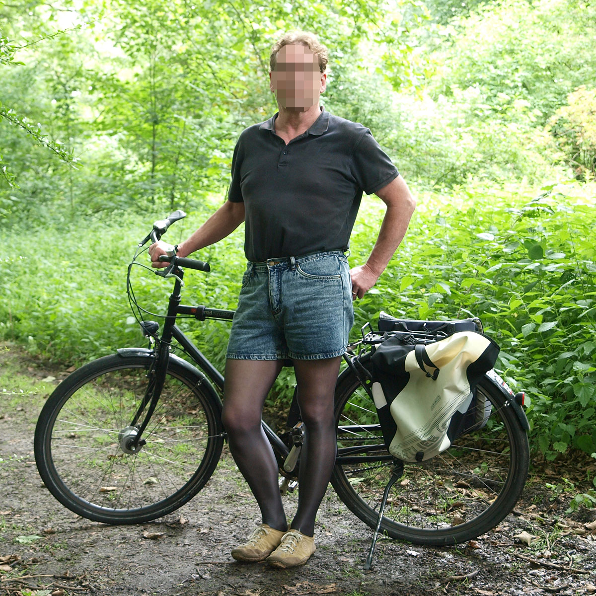 Ein Mann mit einer schwarzen, transparenten Feinstrumpfhose und einem Fahrrad